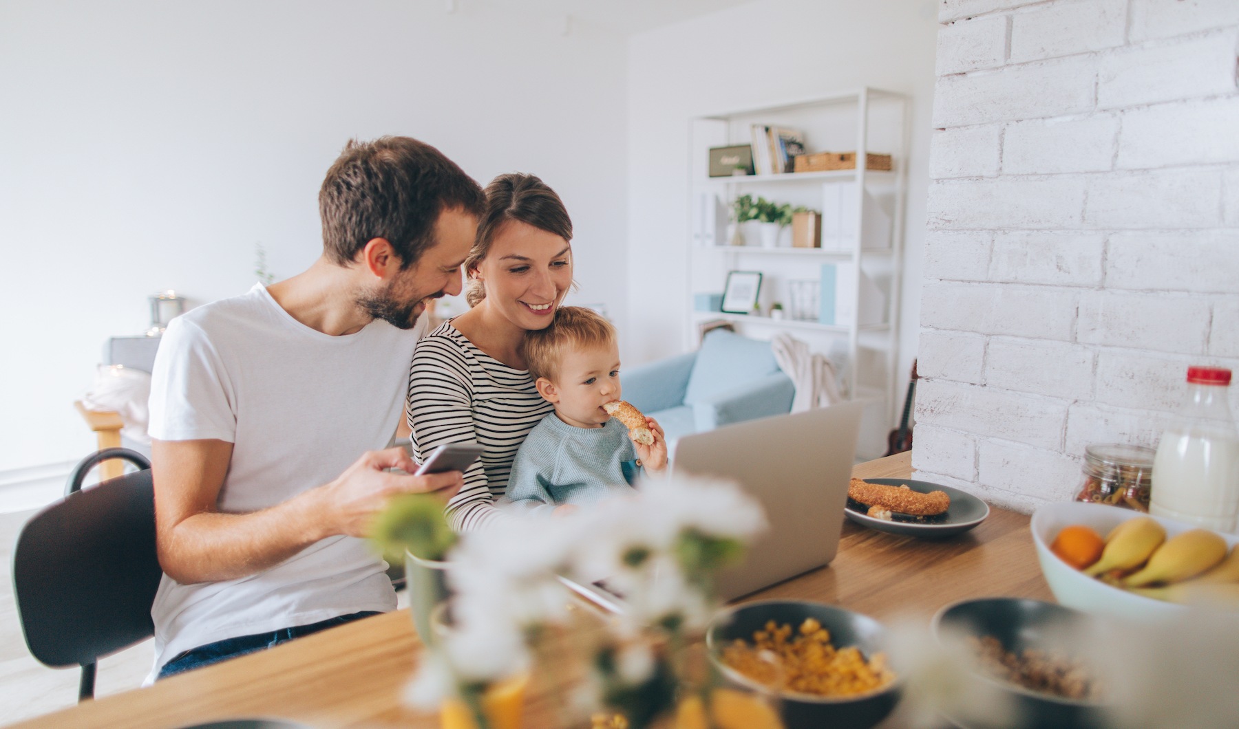 Rotator 3 lifestyle image of couple holding small child looking at a computer while sitting at a table